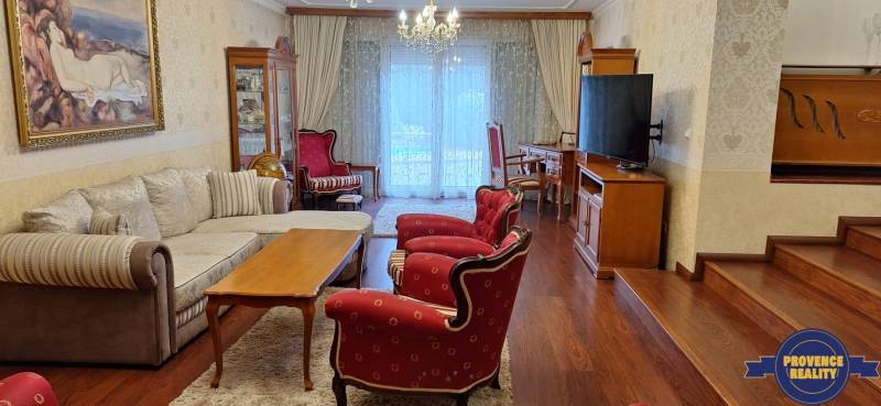 Obývací pokoj v rodinném domě s červenými křesly a podlahou s dřevěným dekorem.