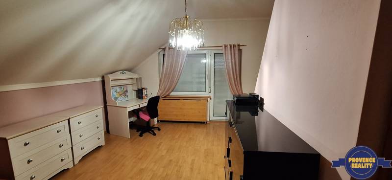 Pokoj s podlahou s dřevěným dekorem, nábytkem a lustrem v rodinném domě.