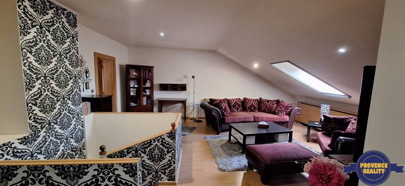 Obývací pokoj s pohovkami a vzorovanými stěnami, podlaha s dřevěným dekorem.