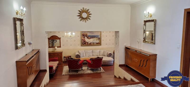 Luxusní interiér rodinného domu s dřevěným dekorem, pohovkou a uměleckými díly na stěnách.