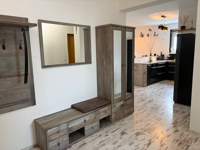 Předsíň s dřevěným dekorem a výhledem do kuchyně ve 3-pokojovém bytě.