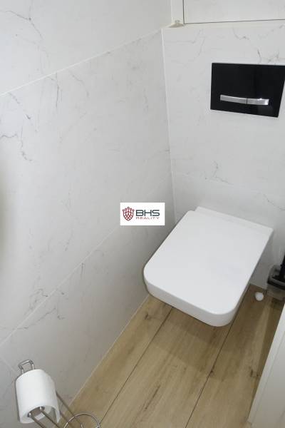 Koupelna s toaletou a podlahou s dřevěným dekorem v 3-pokojovém bytě.