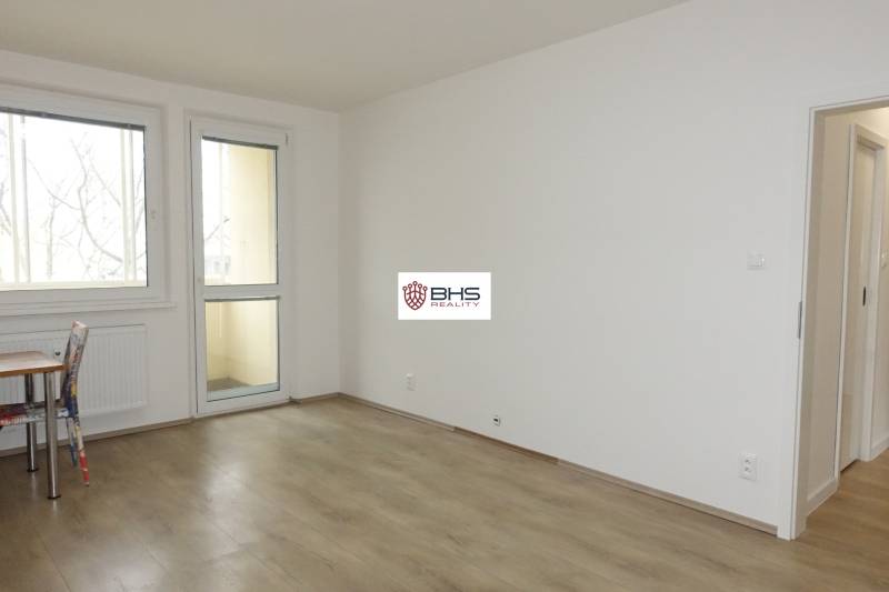 Pokoj s podlahou s dřevěným dekorem v 3-pokojovém bytě, stůl a židle.