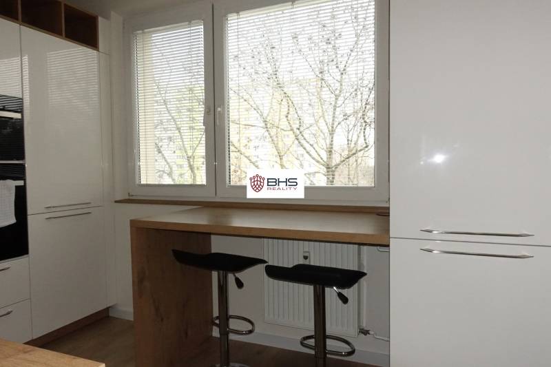 Kuchyně 3pokojového bytu s podlahou s dřevěným dekorem a velkými okny.