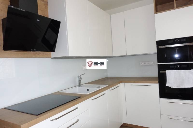 Kuchyně s bílými skříňkami a spotřebiči, doplněná podlahou s dřevěným dekorem v 3pokojovém bytě.