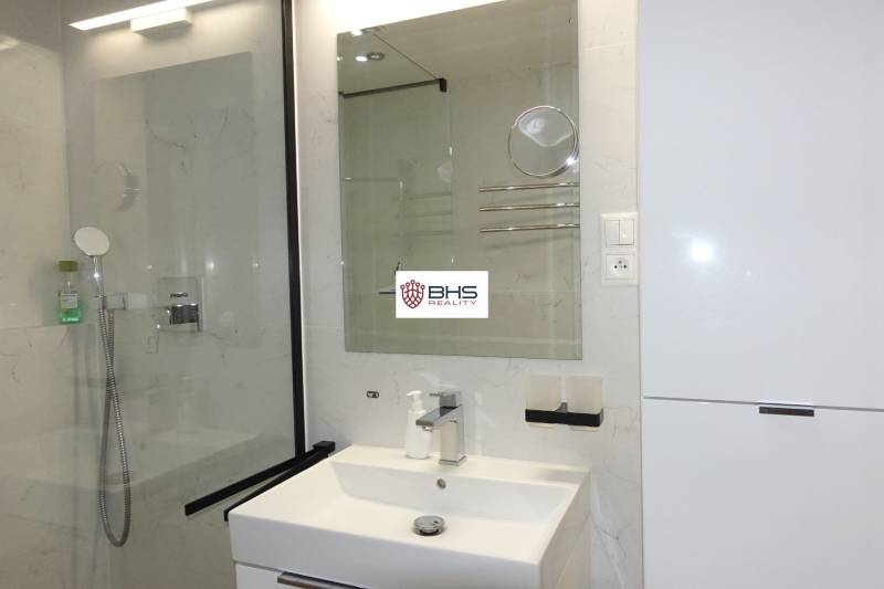 Koupelna ve 3-pokojovém bytě s umyvadlem, zrcadlem a sprchovým koutem.