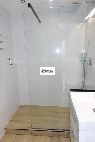 Sprchový kout s prosklením a podlahou s dřevěným dekorem v 3-pokojovém bytě.