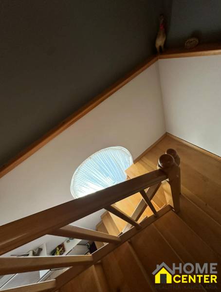 Schodiště s dřevěným dekorem v rodinném domě se schodišťovým zábradlím a kruhovým oknem.