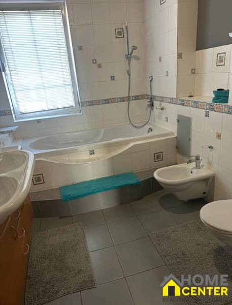 Koupelna v rodinném domě s vanou, bidetem a obklady.