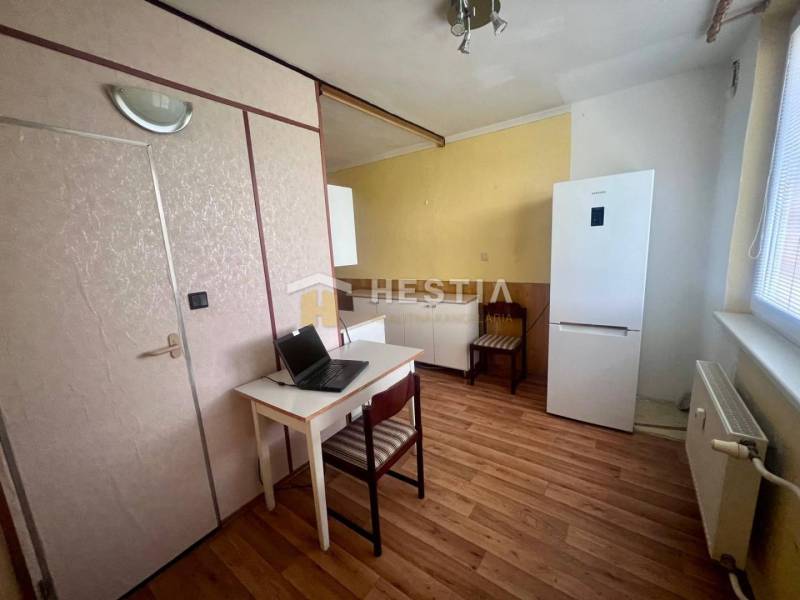 Kuchyně ve 3-pokojovém bytě s pracovním stolem, lednicí a dřevěnou podlahou.