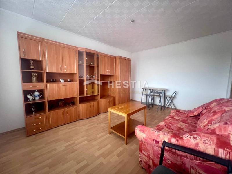 Obývací pokoj v 3-pokojovém bytě s červenou sedačkou a dřevěnou obývací stěnou.