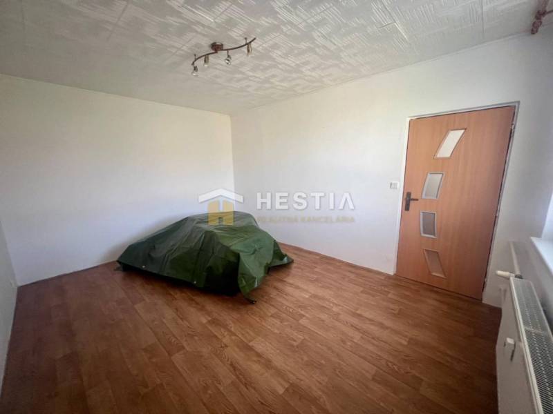 Pokoj ve 3-pokojovém bytě s podlahou, radiátorem, dveřmi a jednoduchým osvětlením.