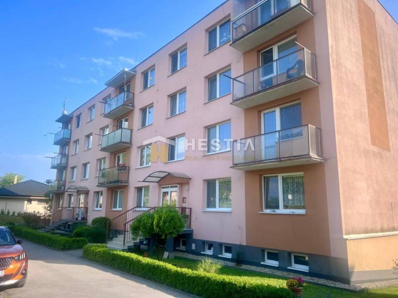 Čtyřpatrový bytový dům v Moravském Lieskovém s balkony a parkováním před budovou.