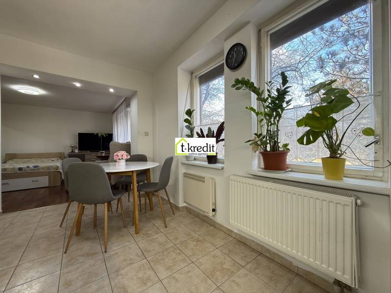 Jídelna v 2-pokojovém bytě s pokojovými rostlinami a kulatým stolem.