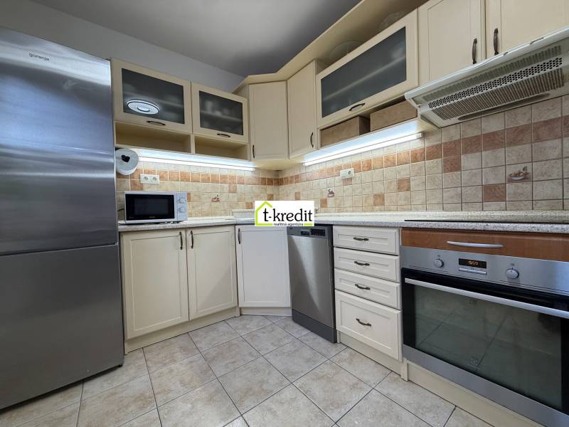 Kuchyně v 2-pokojovém bytě s myčkou, troubou, mikrovlnkou a kachličkovými obklady.