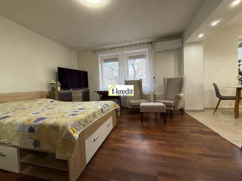 Ložnice v 2pokojovém bytě s podlahou s dřevěným dekorem a pohodlnými křesly.