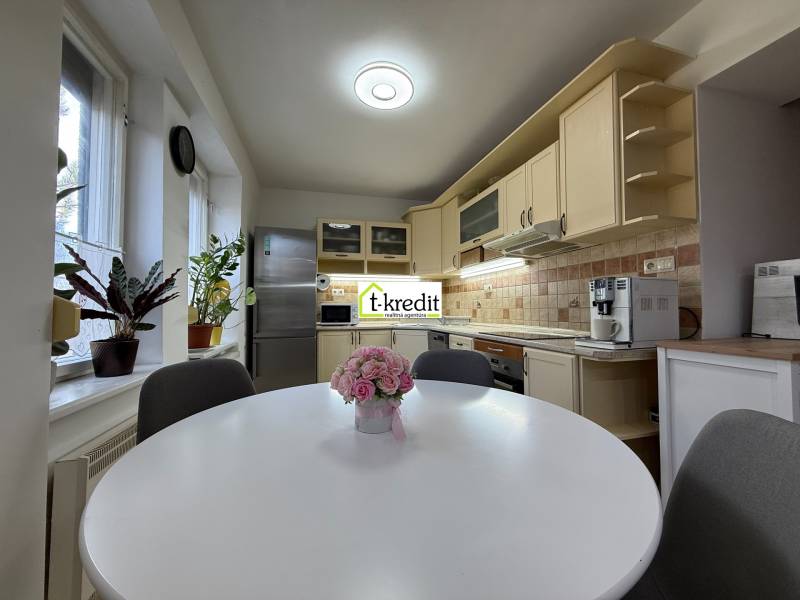 Kuchyně v 2-pokojovém bytě s kuchyňskou linkou, okny a rostlinami.