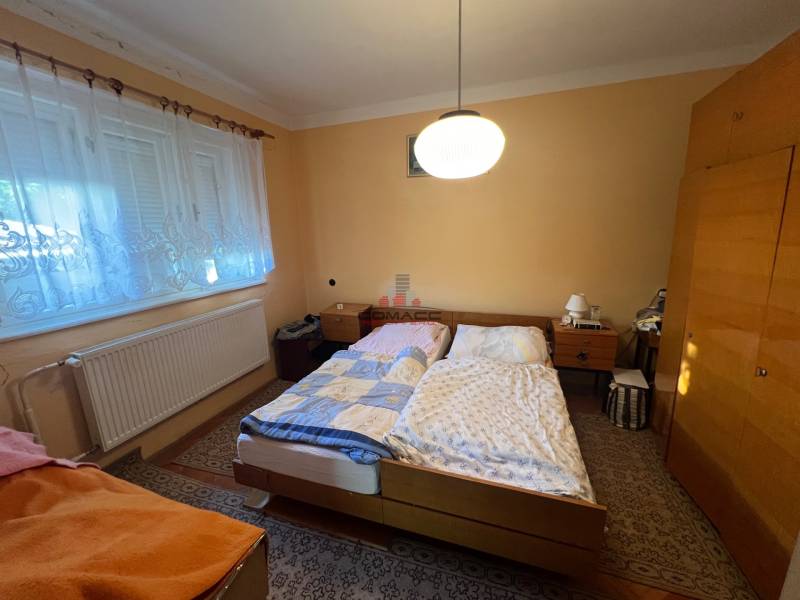 Ložnice v rodinném domě s dvěma postelemi, skříní a kobercem.