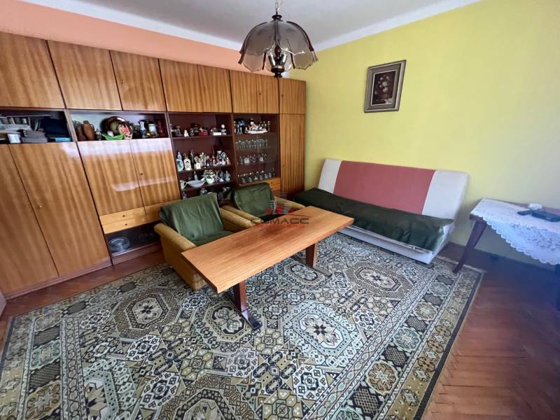 Obývací pokoj v rodinném domě s nábytkem, kobercem a obrazem na stěně.