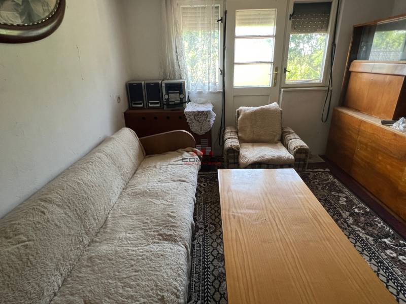 Obývací pokoj v rodinném domě s pohovkou, křeslem a dřevěným nábytkem.