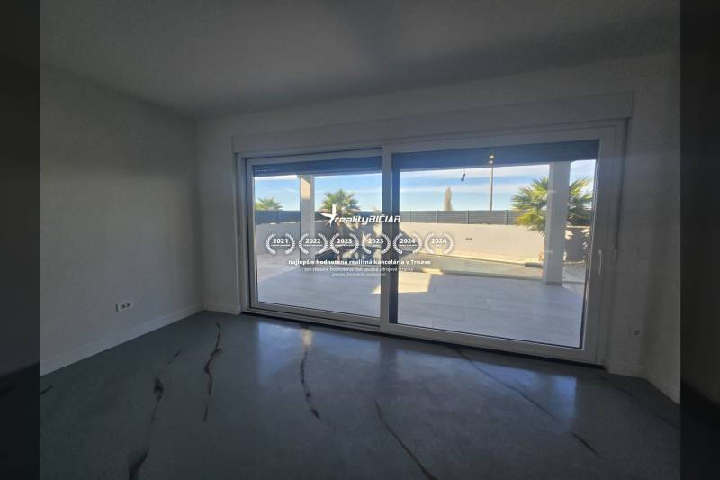 Interiér vily s velkým prosklením a výhledem na exteriér s bazénem.