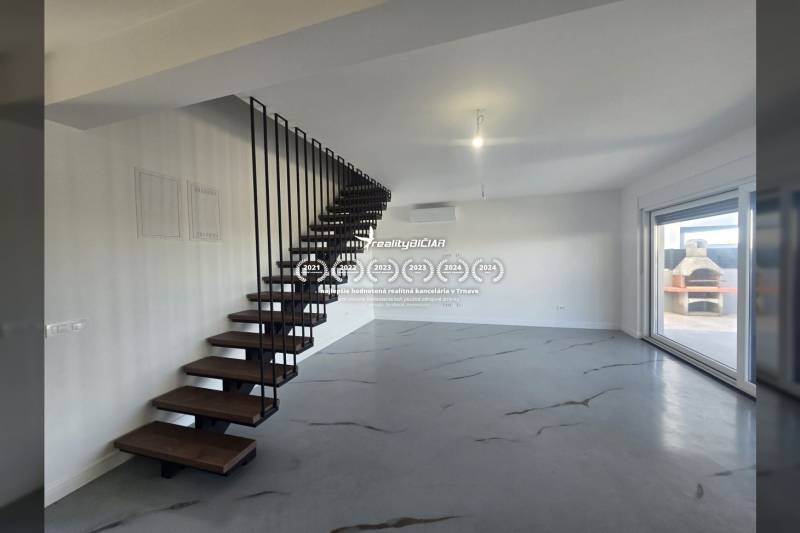 Interiér vily s kovovým schodištěm a podlahou s dřevěným dekorem, velké okno na terasu.