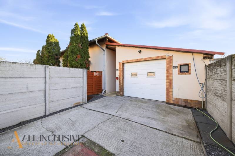 Rodinný dům v Hviezdoslavově s garáží, ohraničený plotem, betonová příjezdová cesta.