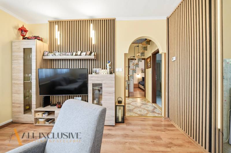 Obývací pokoj v rodinném domě s televizorem a podlahou s dřevěným dekorem.