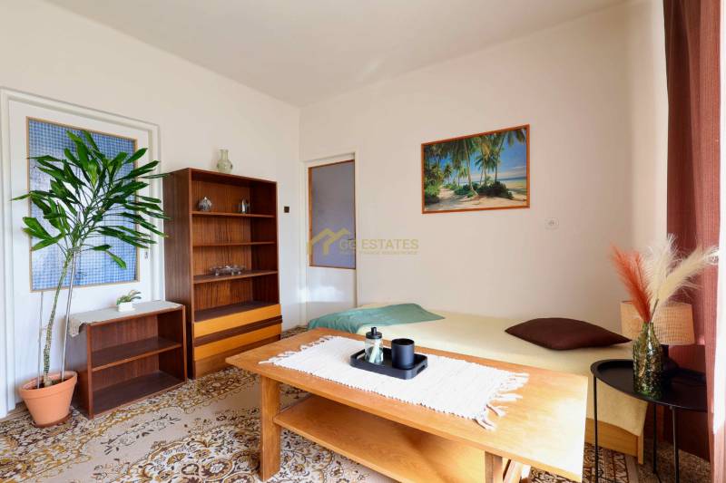 Obývací pokoj v rodinném domě s kobercovou podlahou, dřevěným nábytkem a obrazem pláže.