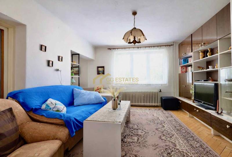 Obývací pokoj v rodinném domě s kobercovým vzorem a nábytkovou stěnou.