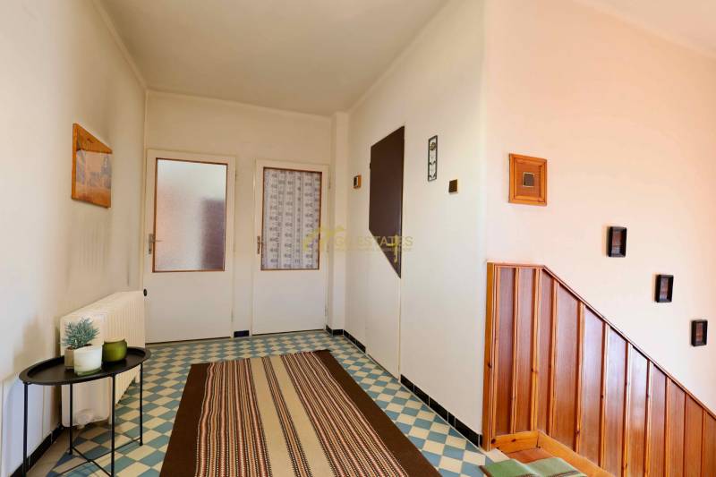 Rodinný dům se vzorovanou dlažbou, dřevěnými schody a jednoduchou dekorací stěn.