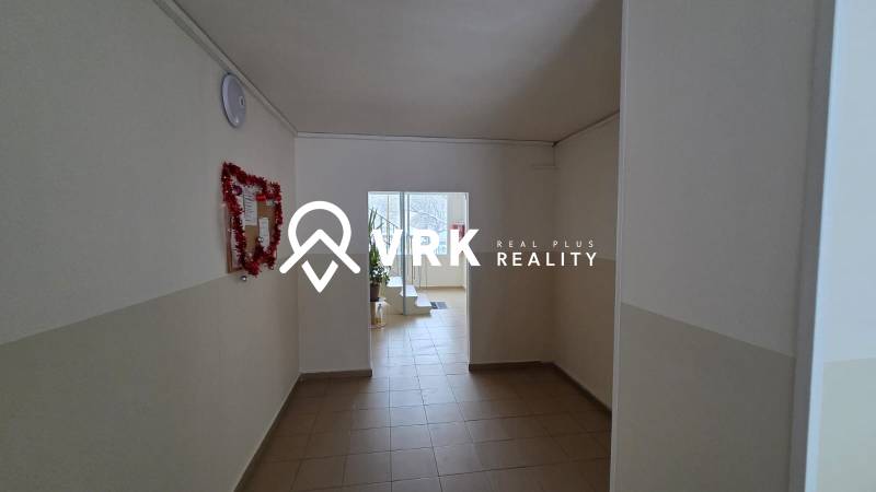 Chodba s bílými stěnami a světlou dlažbou v 3-pokojovém bytě.