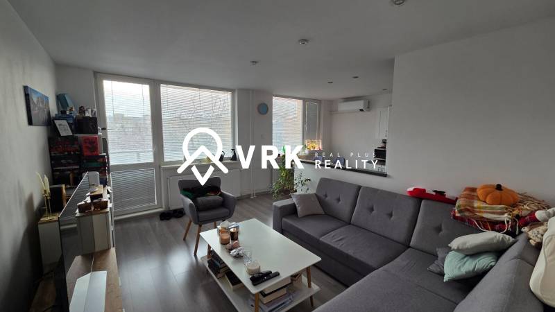 Obývací pokoj 3pokojového bytu s pohovkou, konferenčním stolkem a podlahou s dřevěným dekorem.