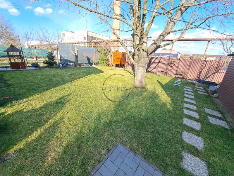 Zahrady v Dolních Krškanech, Nitra s krbem, stromem, trávníkem a stínidlem.