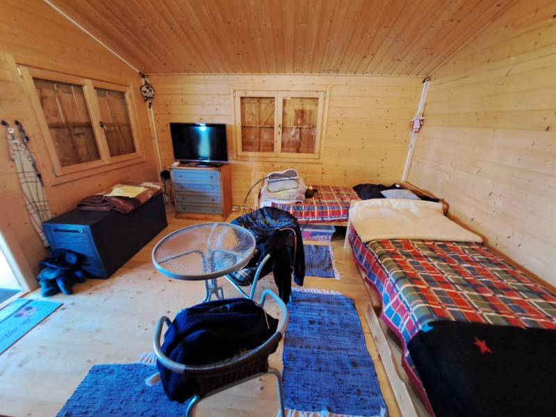 Pokoj v Zahradách se stolkem, židlemi a dvěma postelemi s barevnými přikrývkami.