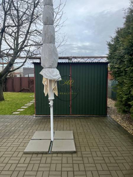 Zahrady v Dolních Krškanech v Nitře se složeným slunečníkem, zpevněnou plochou a trávníkem.