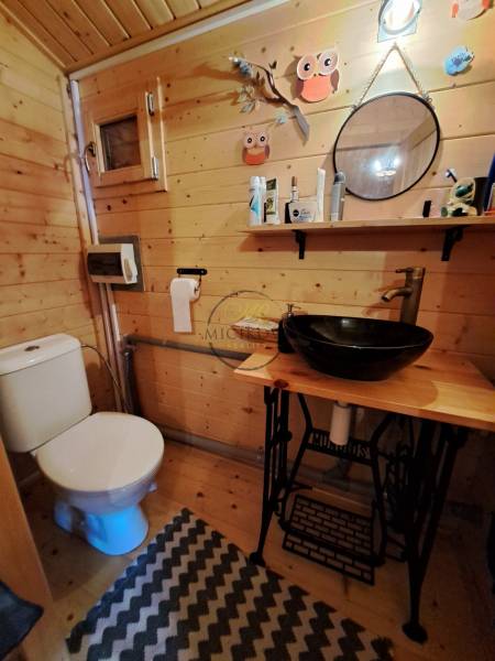 Dřevěný interiér koupelny se zrcadlem, poličkou a umyvadlem v Zahradách.