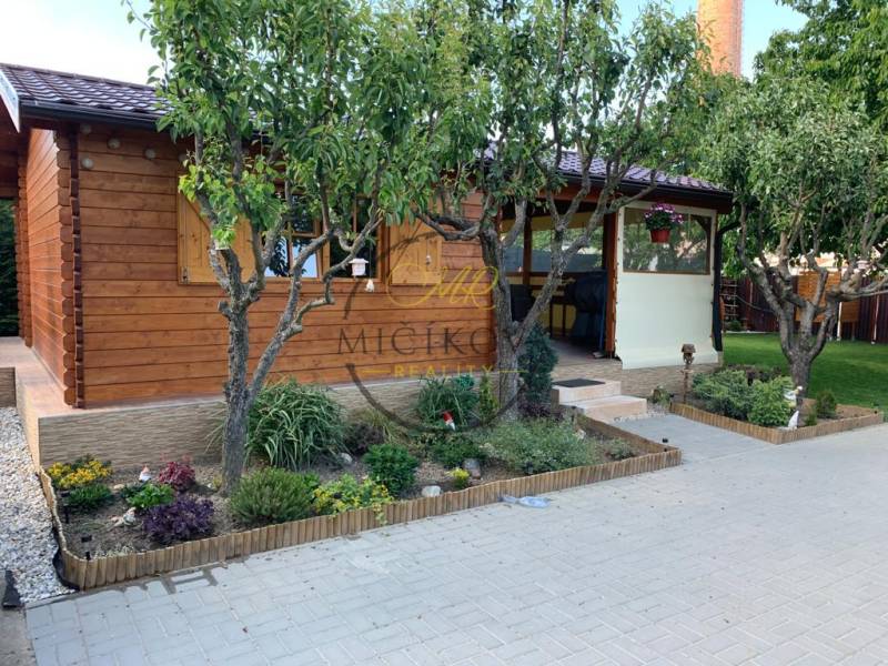 Zahrady v Dolních Krškanech u Nitry s dřevěnou chatkou a upraveným prostorem na odpočinek.