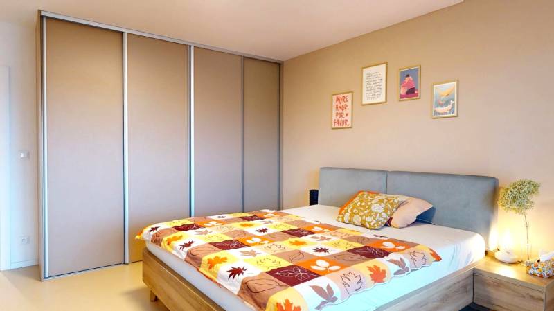 Ložnice v rodinném domě s postelí, vestavěnou skříní a dekorativními obrazy na stěně.