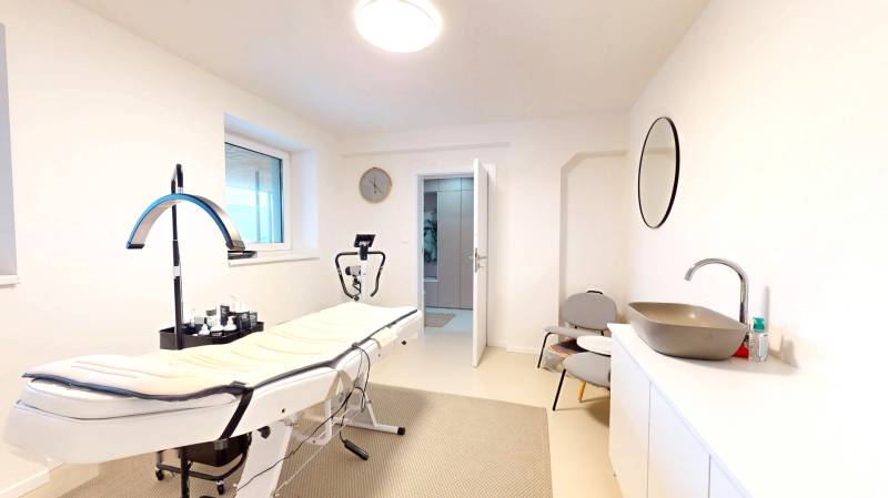 Interiér rodinného domu s masážním stolem, umyvadlo, zrcadlo a židle.