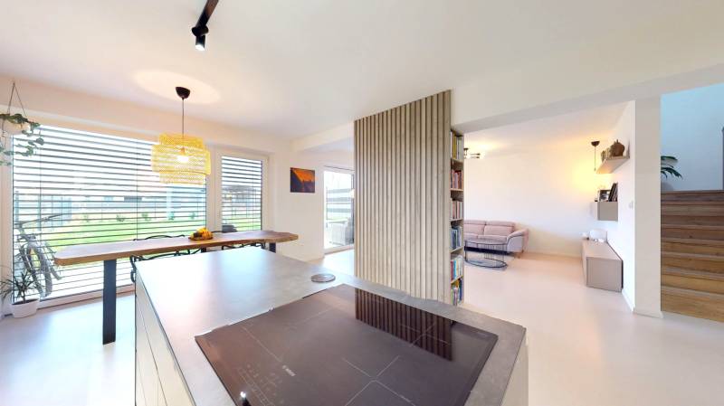 Otevřený interiér rodinného domu s kuchyní, jídelnou a pohodlným obývacím koutem.