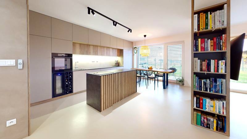 Otevřená kuchyně s jídelním stolem a knihovničkou v rodinném domě.