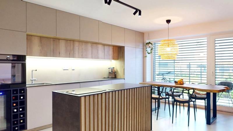 Kuchyně v rodinném domě s dřevěným dekorem nábytku a velkými okny.