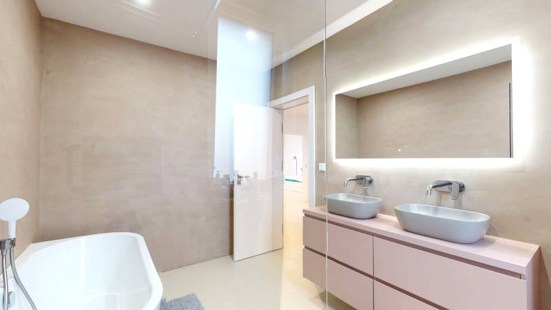 Koupelna s vanou, dvěma umyvadly a zrcadlem v rodinném domě.