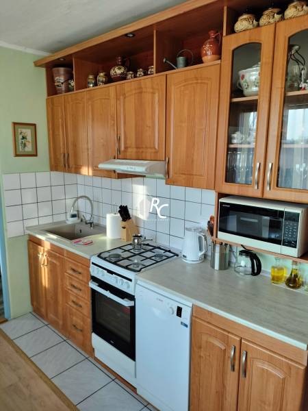 Kuchyně v 2-pokojovém bytě s dřevěnými skříňkami, sporákem a spotřebiči.