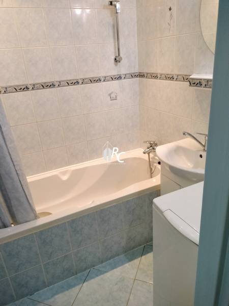 Koupelna v 2-pokojovém bytě s vanou a světlými obklady.