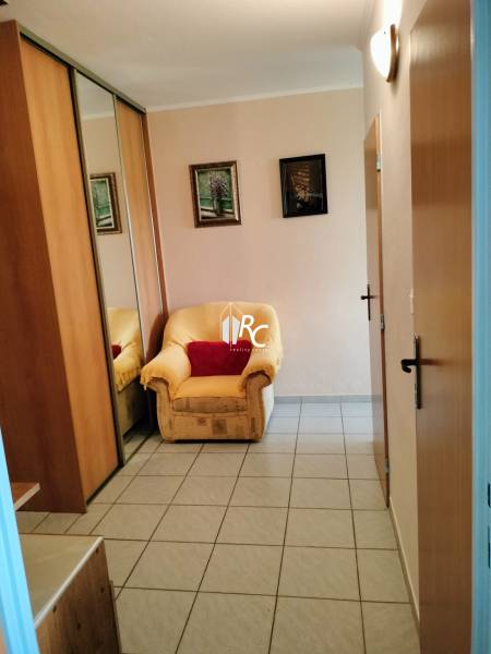 Křeslo u vchodových dveří s dlaždicovou podlahou ve 2-pokojovém bytě, zrcadlová skříň.