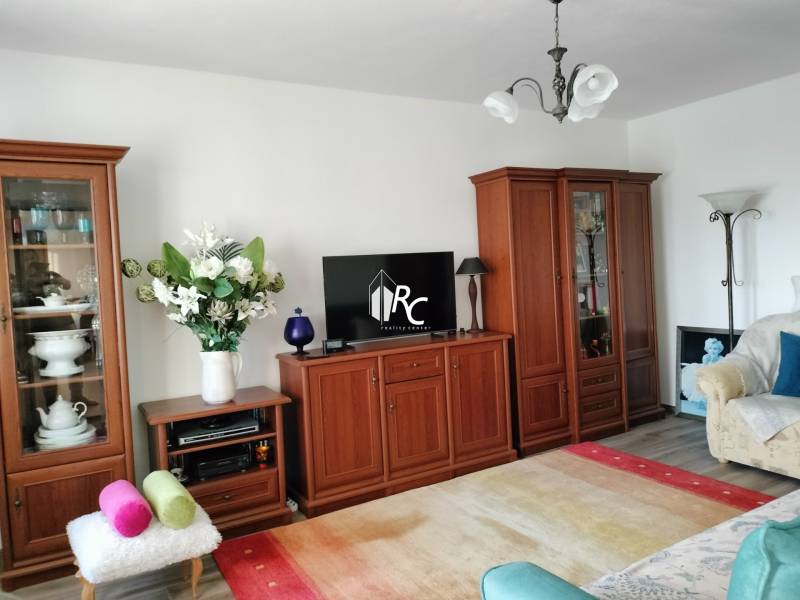 Obývací pokoj v 2pokojovém bytě s dřevěným dekorem a světlým interiérem.