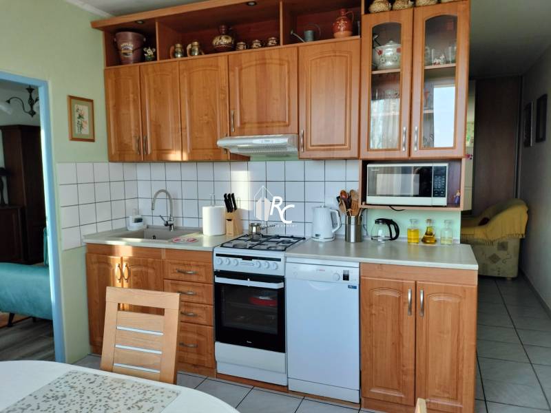 Kuchyně v 2pokojovém bytě s dřevěným dekorem, vybavená spotřebiči a úložným prostorem.