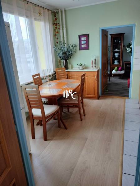 Jídelní kout v 2-pokojovém bytě s podlahou s dřevěným dekorem a světlým nábytkem.